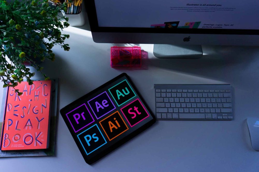 Photo of a graphic designer's desk with Adobe programs opened up on a tablet.